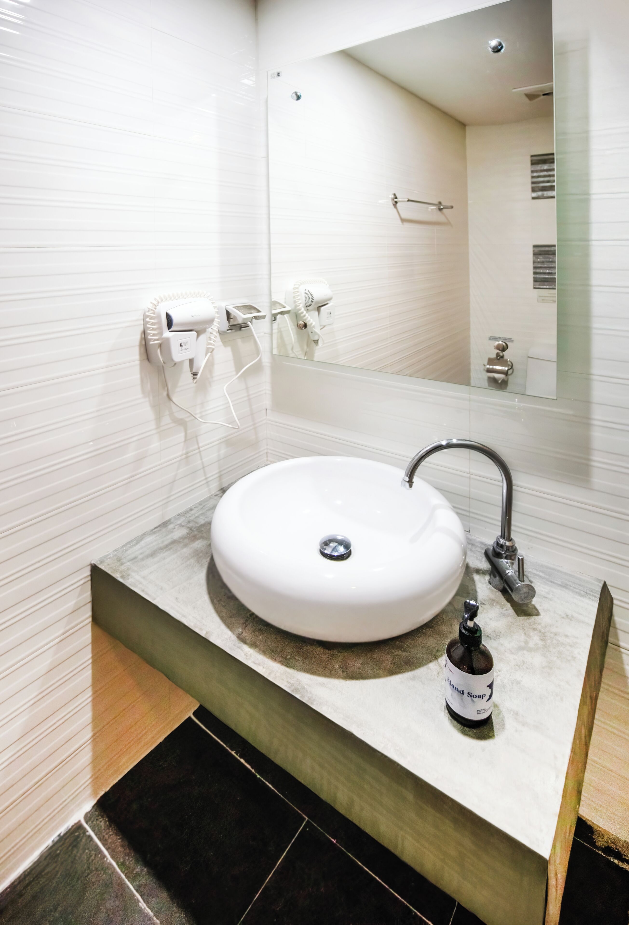 A bathroom with a white sink, a mirror, and a bottle of hand soap.