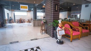 A restaurant interior with a waiter statue, dining tables, chairs, and a sign indicating restaurant hours.