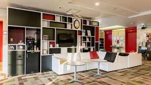 A modern lounge area with a white sofa, a coffee machine, and a TV mounted on the wall. - KOKO STAY Chitose (Chitose)