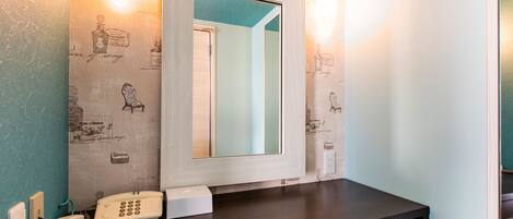 A bathroom with a mirror, a telephone, and a tissue box on a dark countertop.