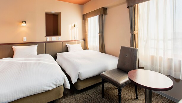 A hotel room with two beds, a chair, a small table, and a mirror. - KOKO STAY Chitose (Chitose)