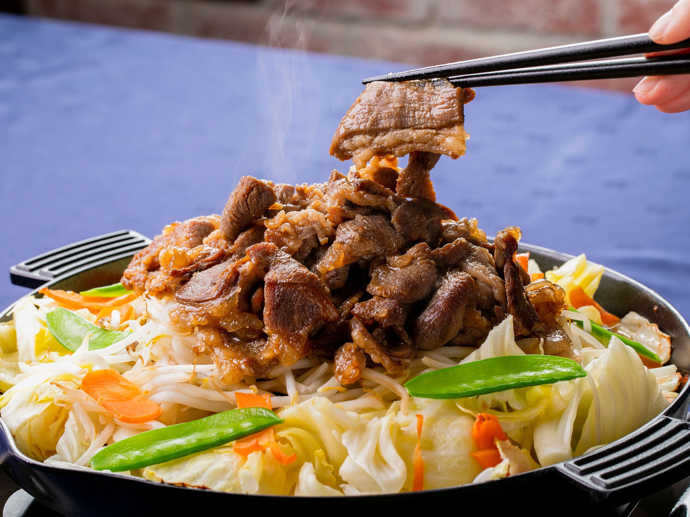 A bowl of stir-fried beef with vegetables.