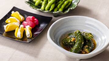 A plate with pickled vegetables and a bowl of soy sauce with vegetables.
