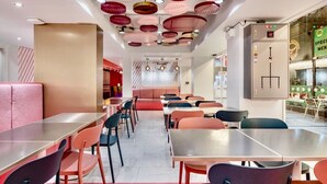 A modern restaurant interior with a long counter, multiple tables, and chairs. - Budacco (Bangkok)