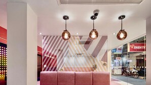 A modern interior with a pink sofa, pendant lights, and a geometric patterned wall. - Budacco (Bangkok)