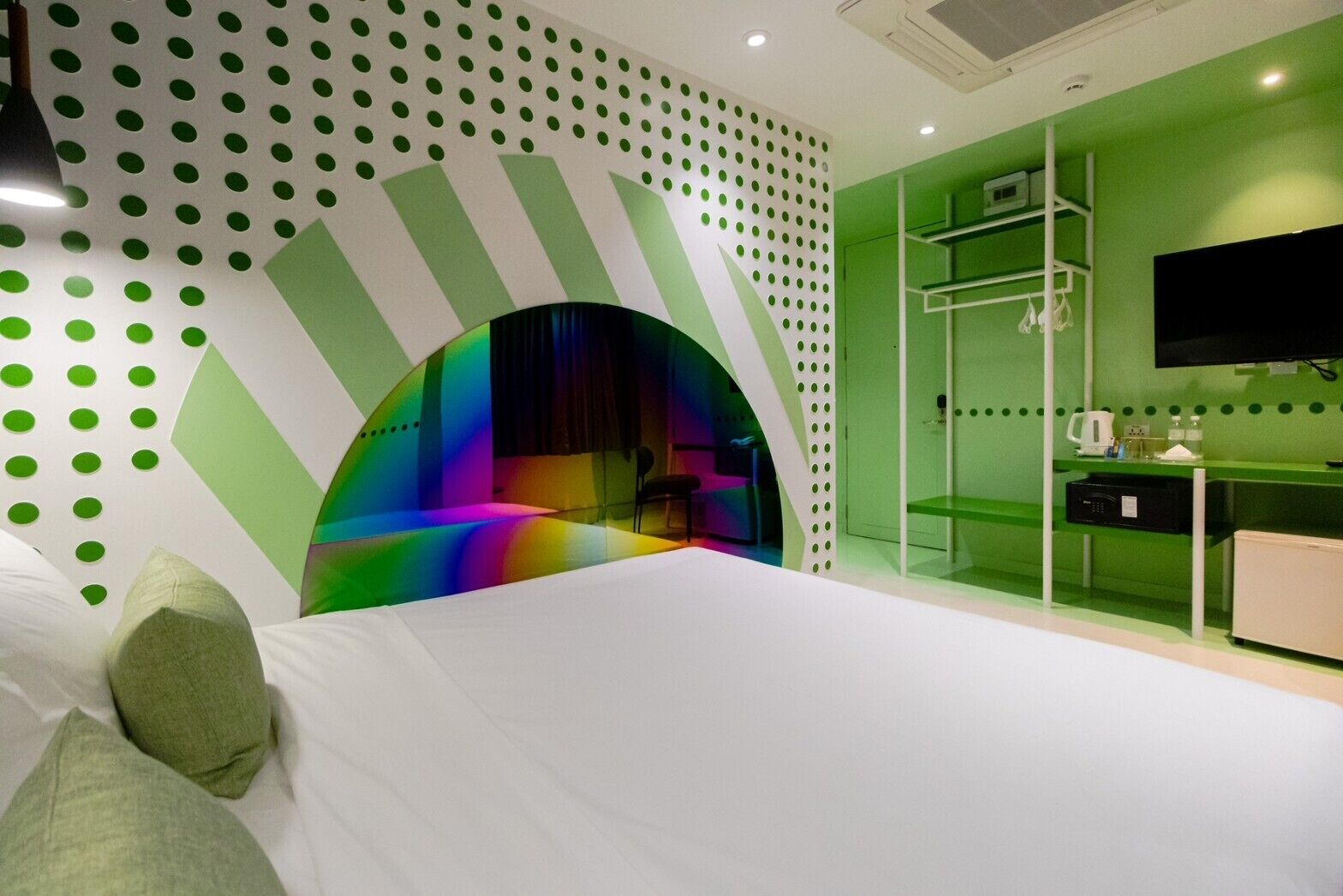 A modern bedroom with a curved wall design, a bed, a TV, and a desk area.
