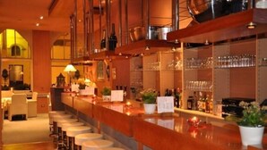 Un espace bar avec des tabourets, un comptoir et des étagères remplies de bouteilles et de verres.