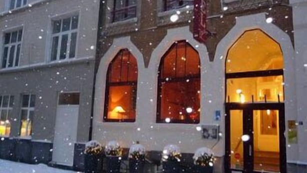 Un bâtiment doté de fenêtres en arc de cercle et dont l’intérieur est éclairé, entouré de neige.