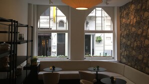 Un intérieur chaleureux avec un canapé, deux petites tables et un luminaire suspendu.