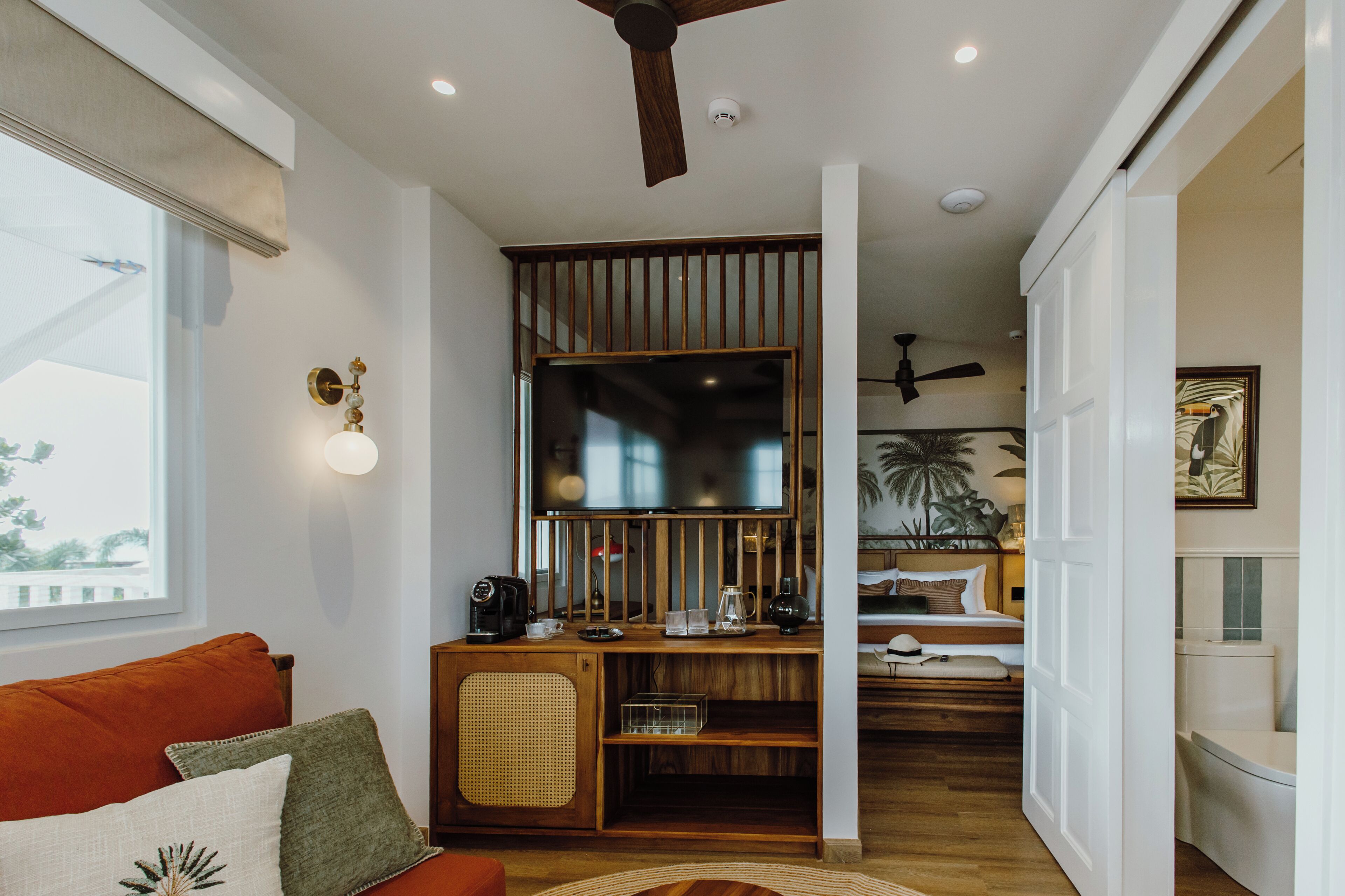 A modern interior with a wooden desk, a bed, and a ceiling fan.