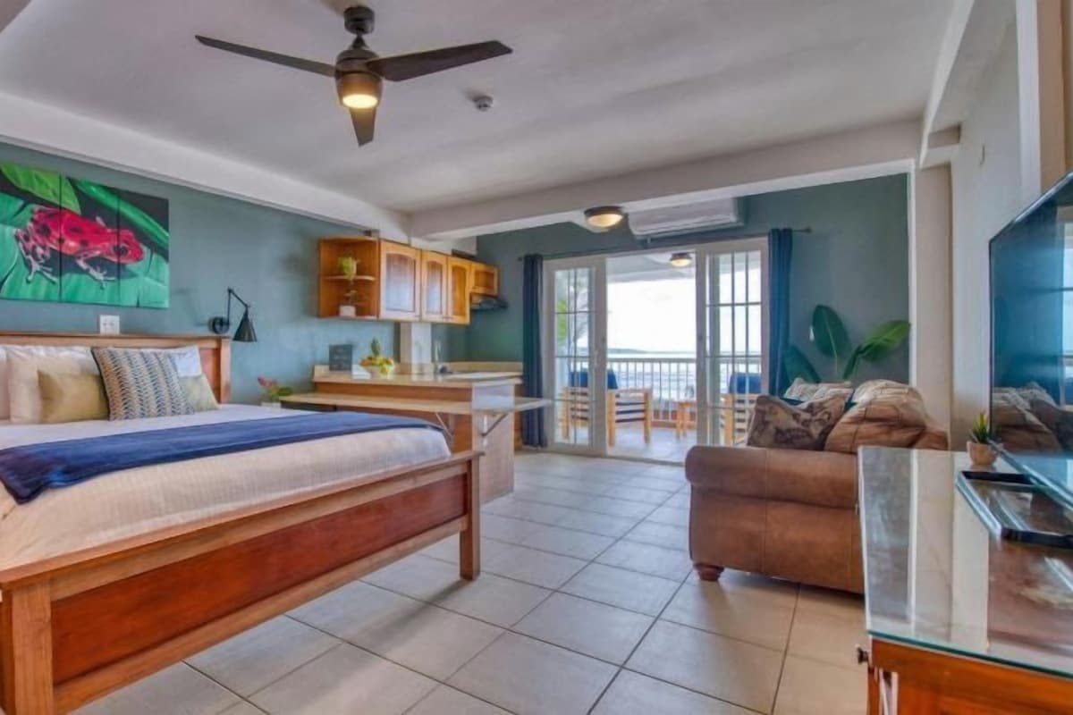 A spacious bedroom with a large bed, a ceiling fan, and a view to a balcony.