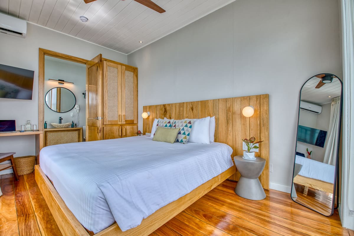 A bedroom with a large bed, wooden headboard, bedside tables, a mirror, and a ceiling fan.