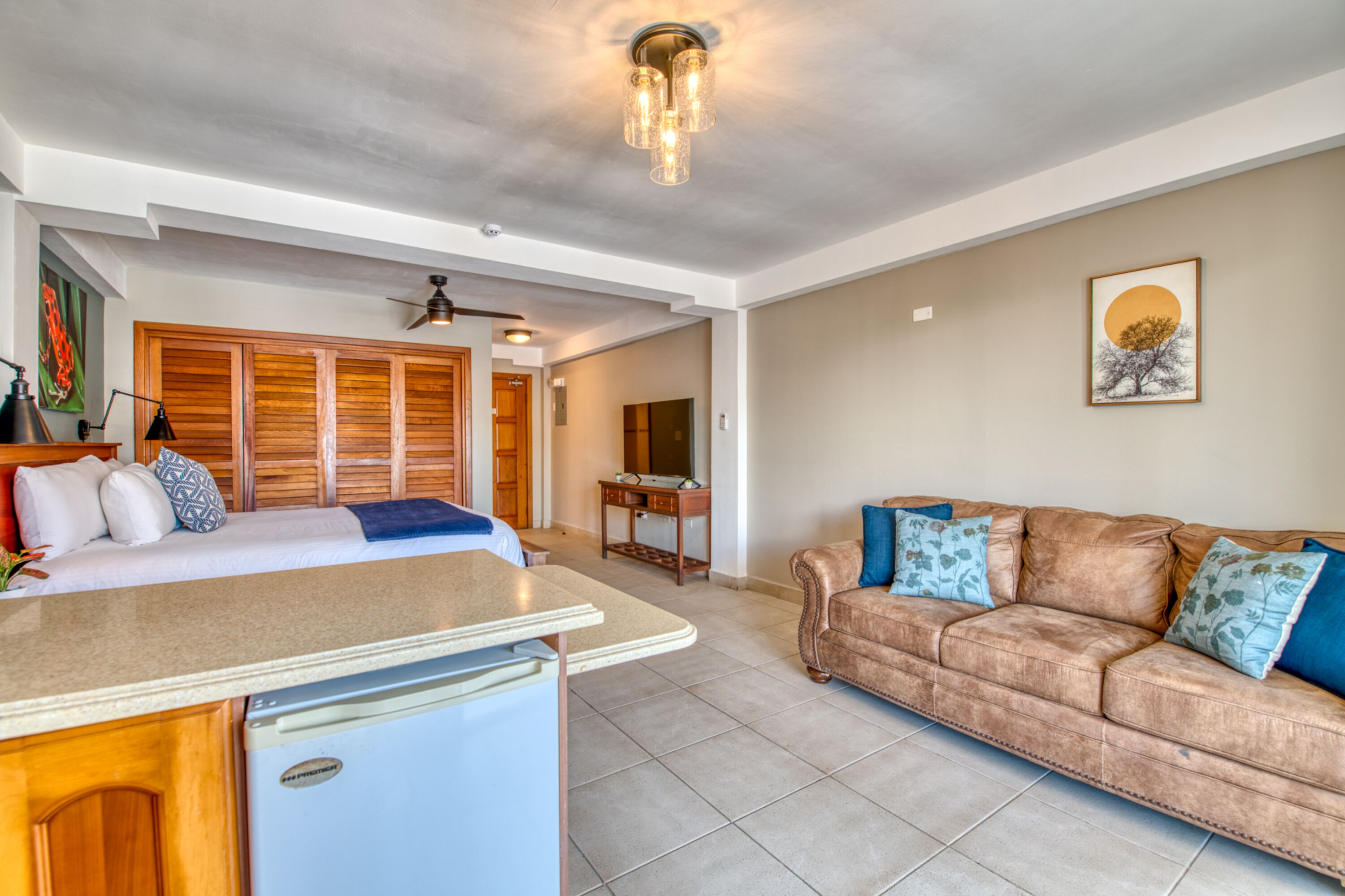 Amplia sala de estar con kitchenette, un sofá de cuero marrón y una mesa de comedor.