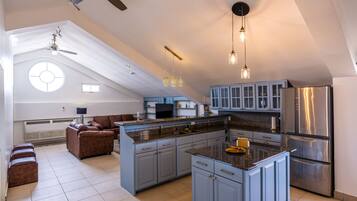 A spacious kitchen with a large island, blue cabinets, and a stainless steel refrigerator.