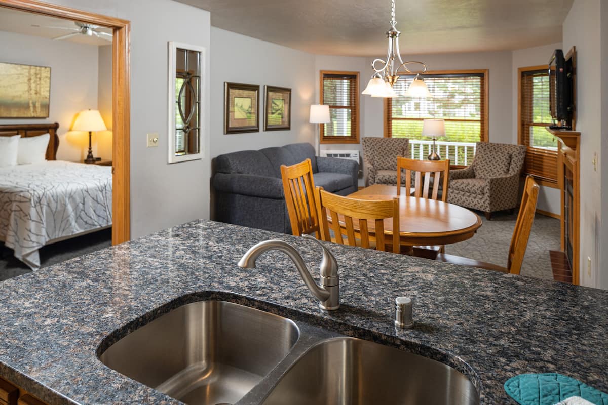 Una cocina con encimeras de granito, un lavabo doble y un comedor con mesa y sillas.