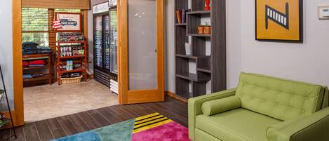 A living room with a green sofa, a colorful rug, a bookshelf, and a door leading to a storage area.