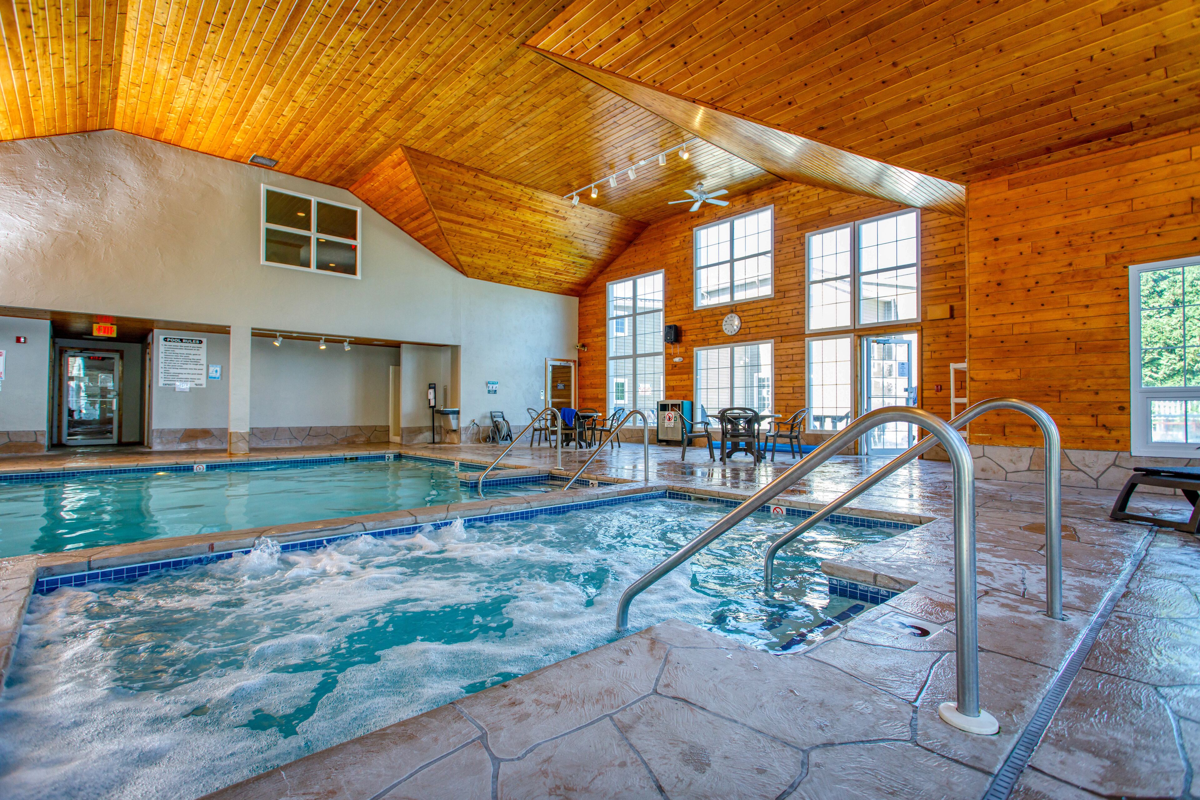 An indoor swimming pool with a wooden ceiling and large windows.