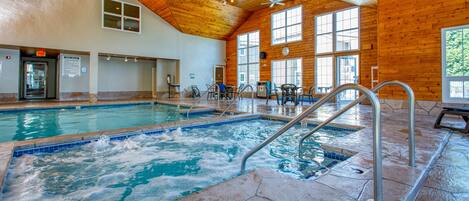 An indoor swimming pool with a wooden ceiling and large windows.
