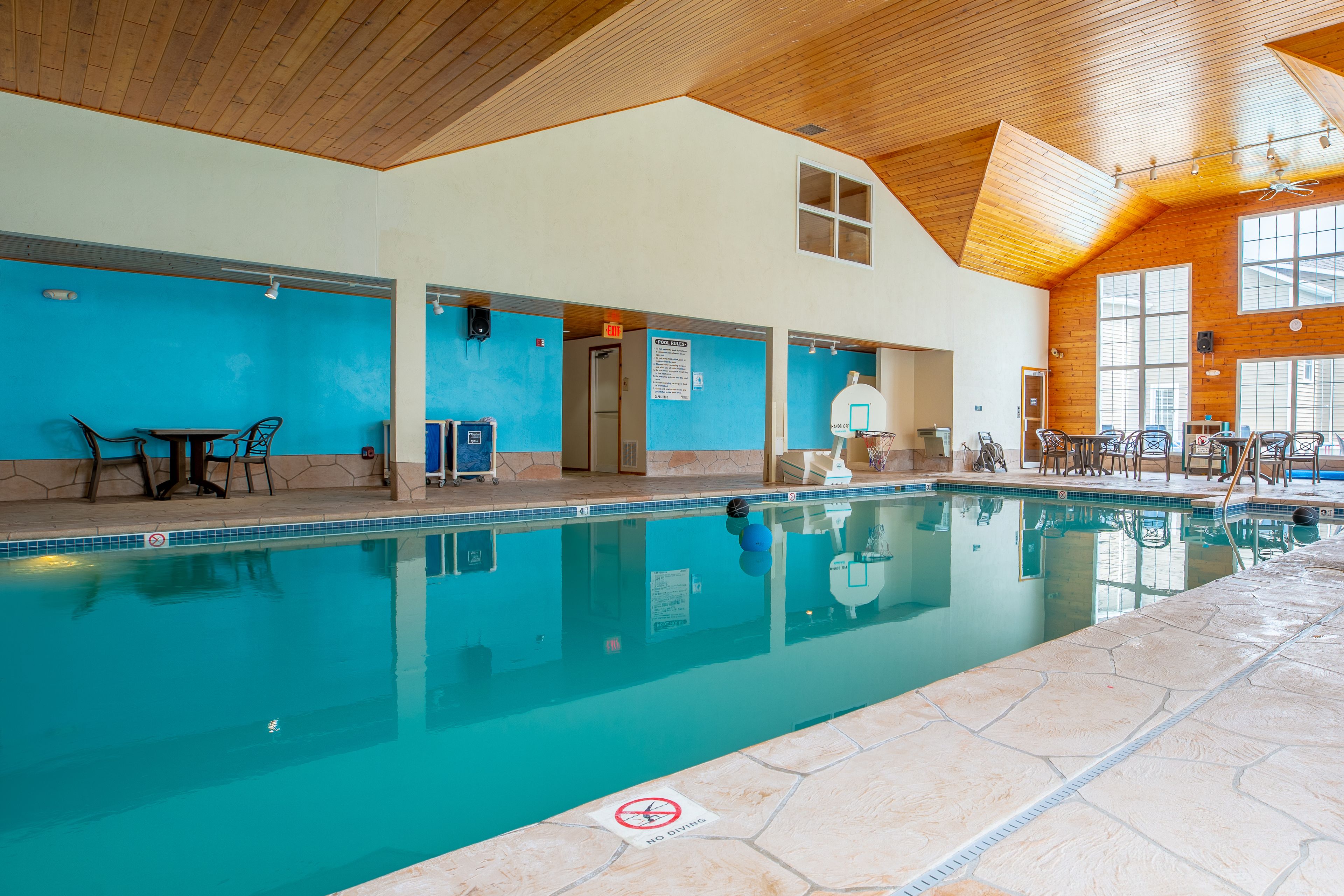 An indoor swimming pool with clear water, wooden ceiling, and blue walls.
