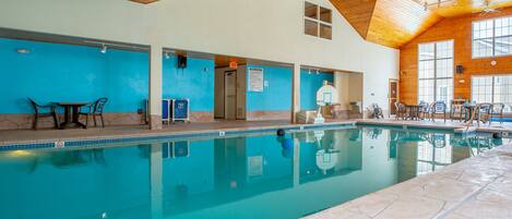 An indoor swimming pool with clear water, wooden ceiling, and blue walls.