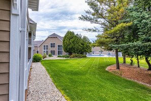 A residential area with a well-maintained lawn, a large house with a porch, and a fenced pool area.