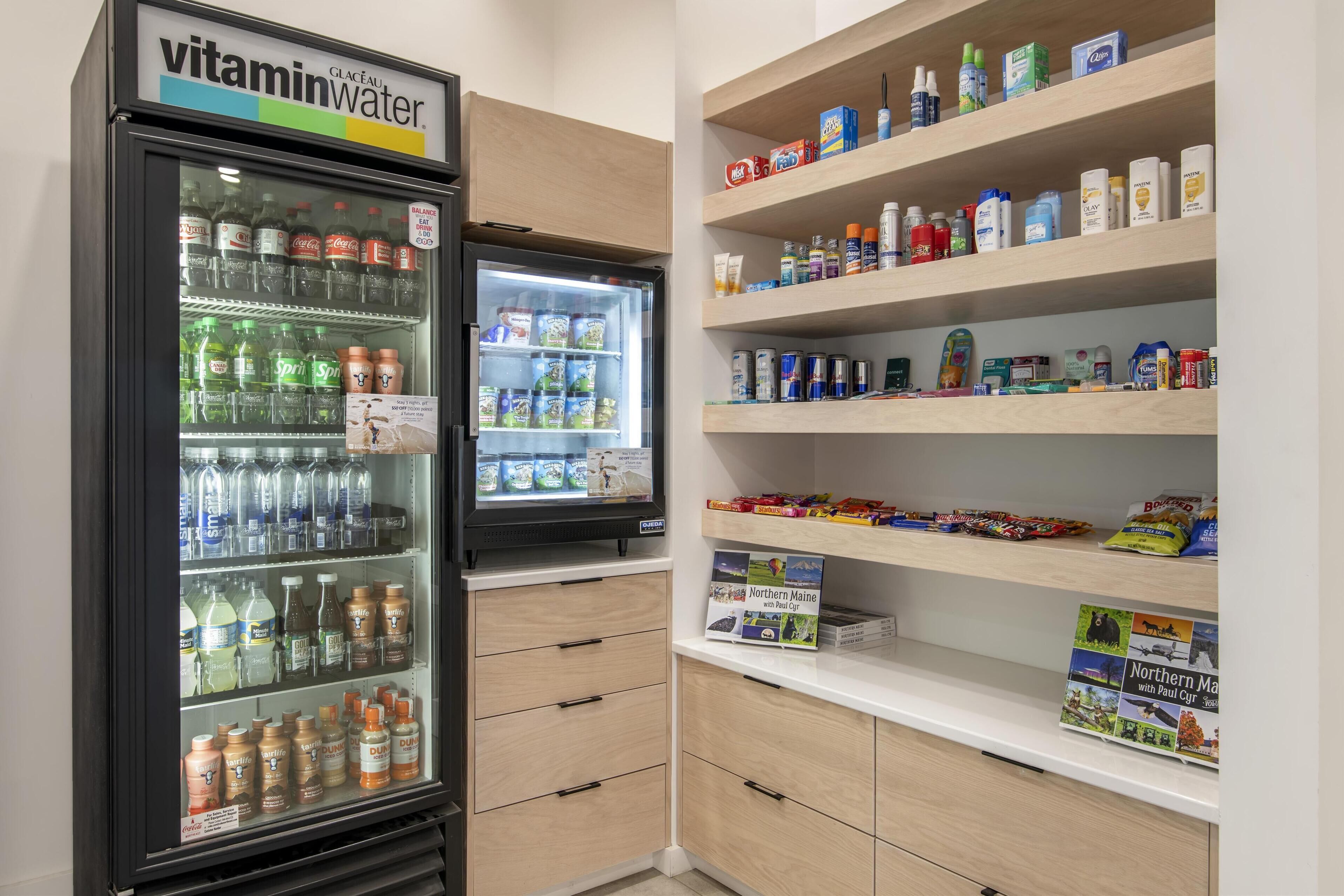 A refrigerated display with various beverages and a shelf stocked with personal care items.