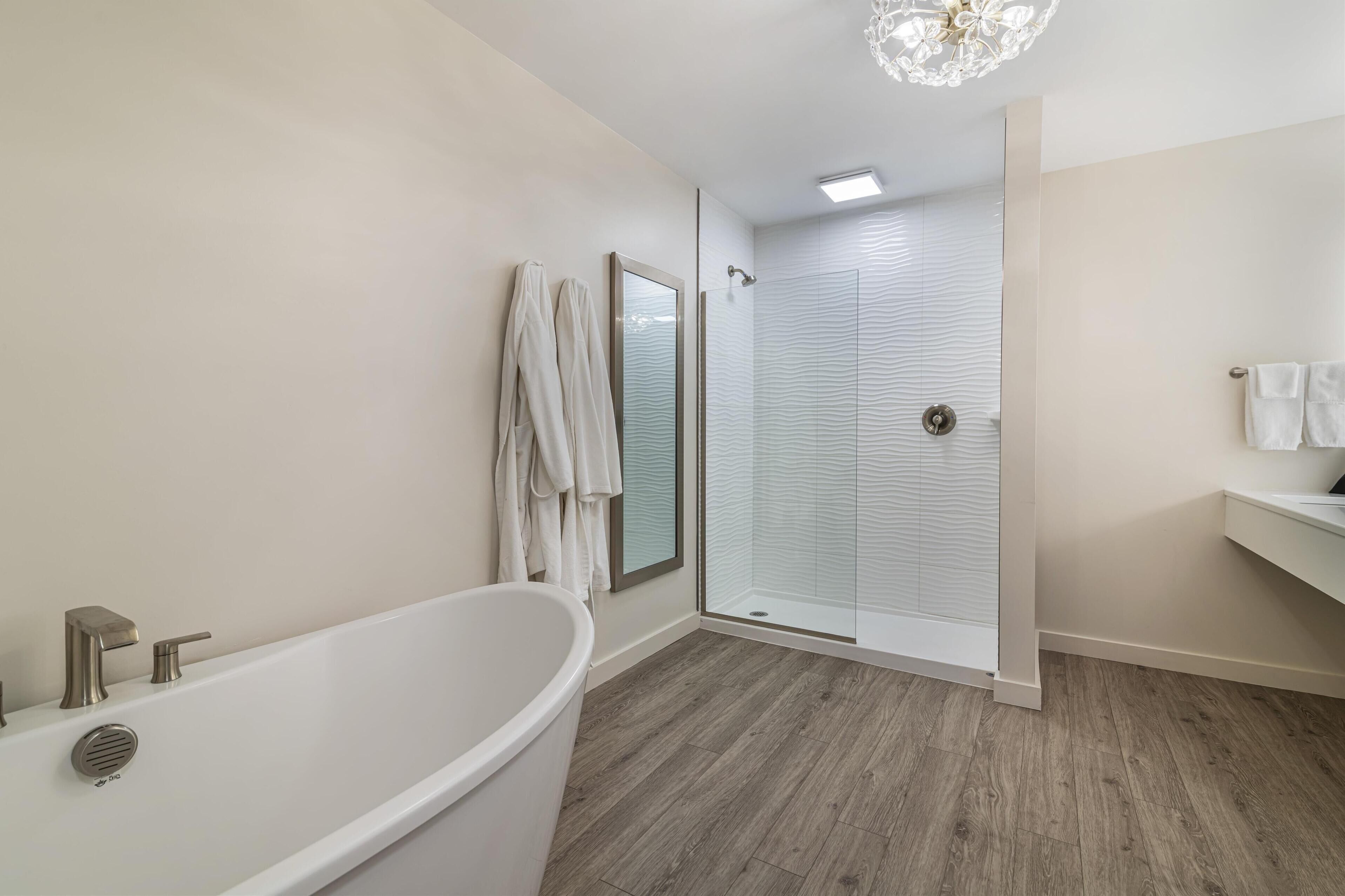 Ein modernes Badezimmer mit freistehender Badewanne, einer Glasdusche und einem integrierten Waschtisch mit Spiegel.