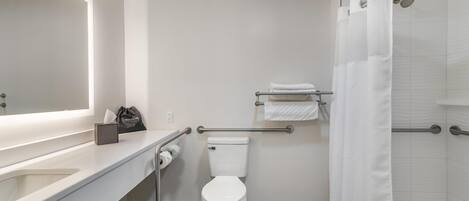 A modern bathroom with a white toilet, a sink with a mirror, a towel rack, and a shower with a curtain.