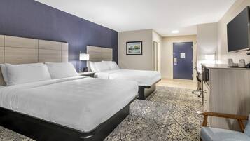 Une chambre d’hôtel avec deux lits, un bureau, une chaise, une télévision et un tableau au mur.