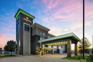 A hotel with a modern design, featuring a prominent 'La Quinta' sign, a covered parking area, and a well-maintained lawn.