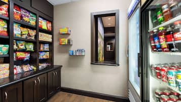 A snack bar with shelves of chips and a refrigerator stocked with sodas.
