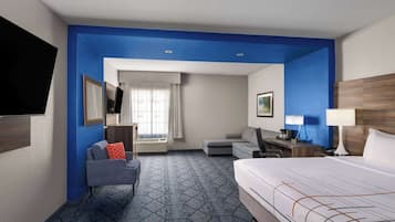 Une chambre d’hôtel avec un lit, un bureau, une chaise, une télévision et une fenêtre avec des rideaux.