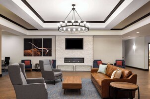 A modern lobby with a fireplace, comfortable seating, and a large TV screen.