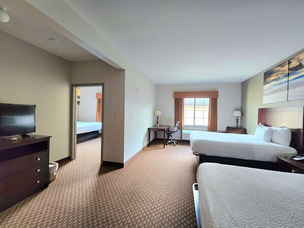 A hotel room with two beds, a desk, a chair, a TV, and a painting on the wall. - Days Inn by Wyndham Kemah (Kemah)
