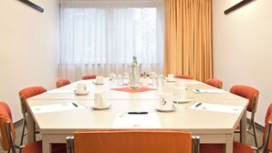 Un salón de conferencias con una mesa larga, sillas y una estación de café.