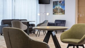 Une chambre d’hôtel avec un lit, une table ronde et deux fauteuils.