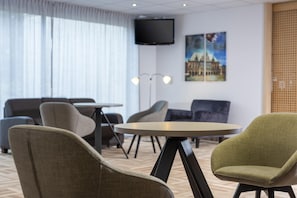 Een hotelkamer met een bed, een ronde tafel en twee fauteuils.