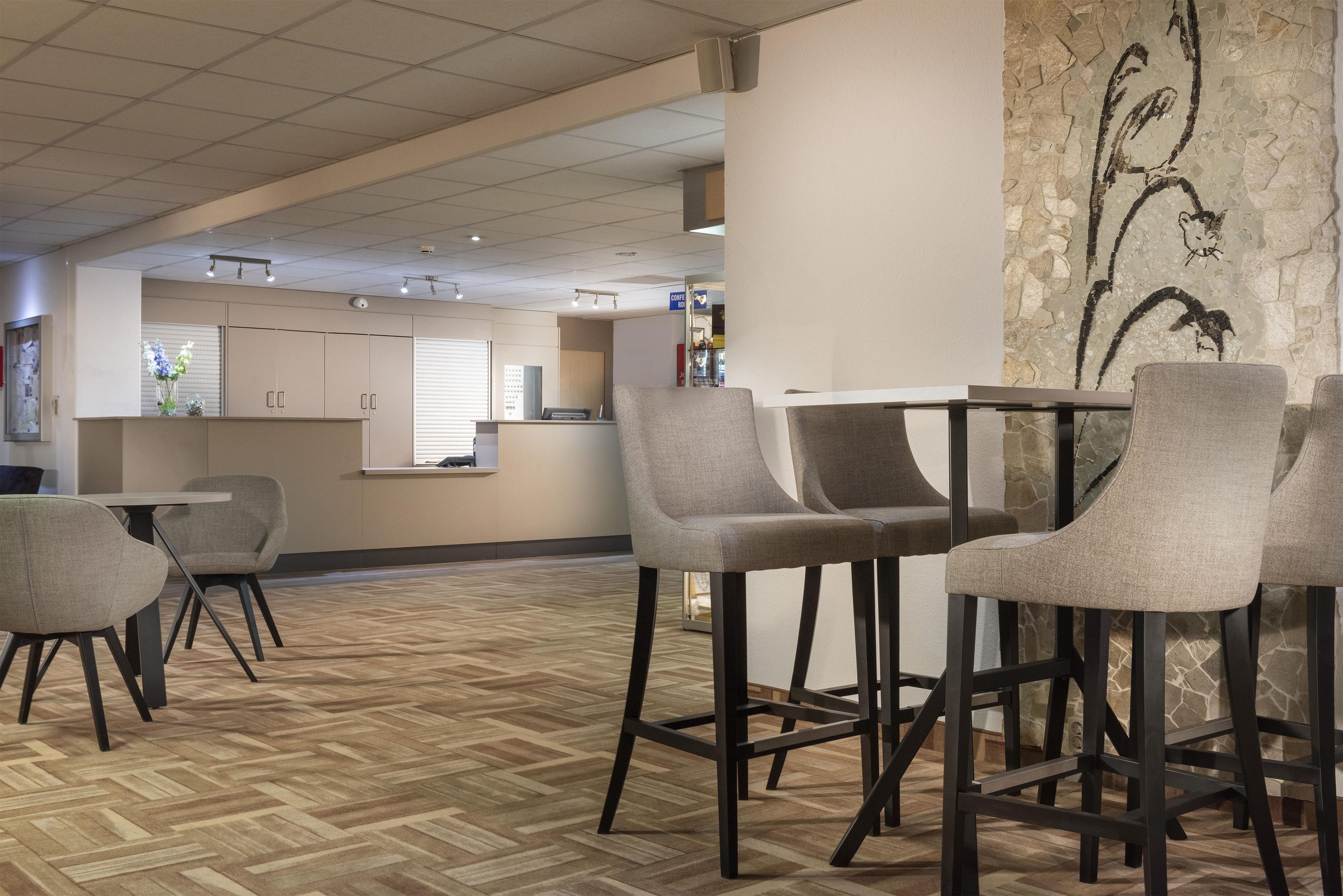 Et hotel lobby med barområde, siddepladser og udsigt til køkkenet i baggrunden.