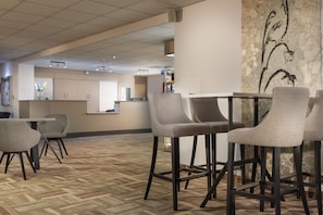 Een hotellobby met een bar, zitplaatsen en een uitzicht op de keuken op de achtergrond.