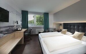 Une chambre d’hôtel moderne, dotée d’un grand lit, d’un bureau, d’une chaise, d’une télévision et d’une fenêtre avec des rideaux.