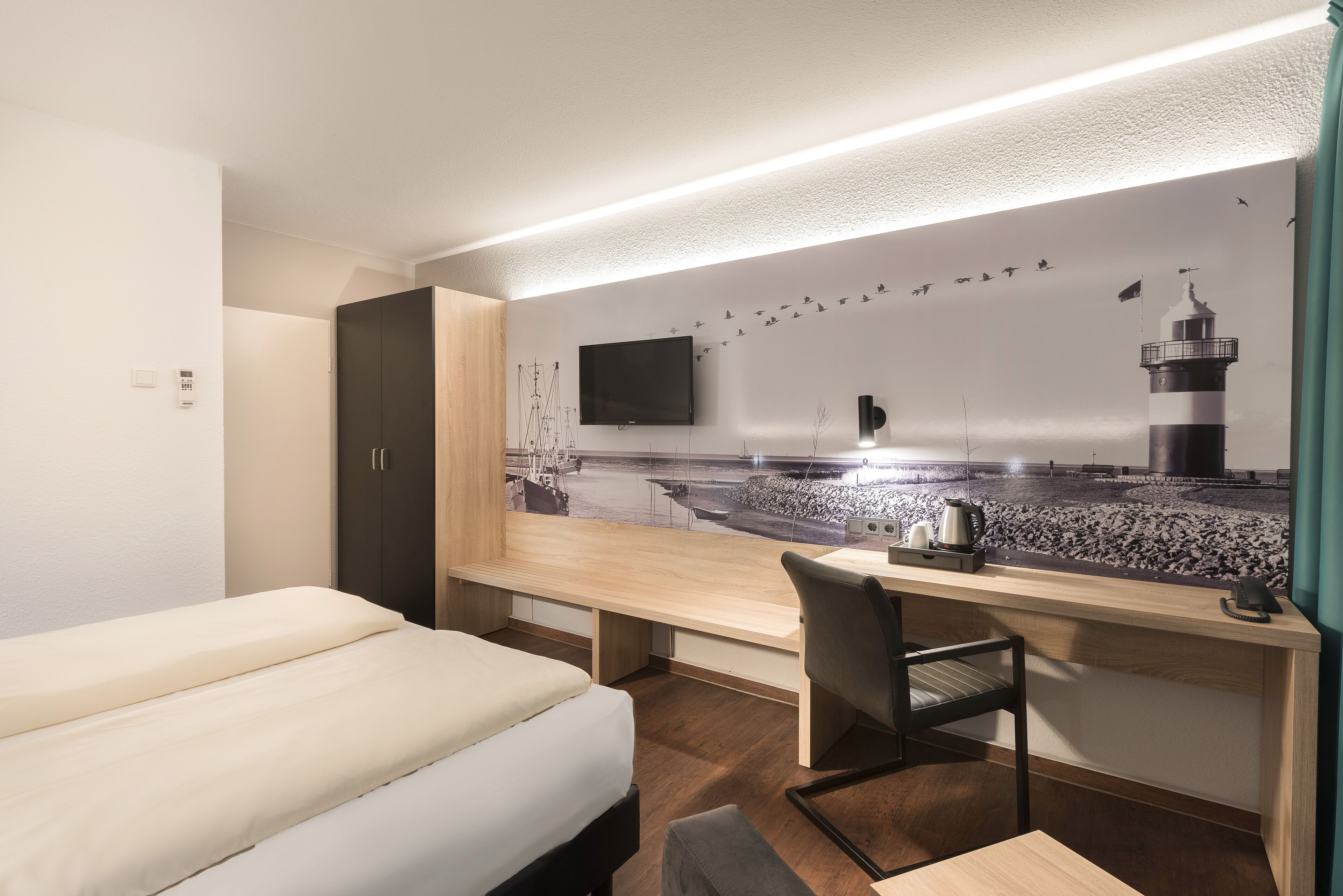 Habitación de hotel con cama, escritorio, silla, televisión y un mural en la pared.
