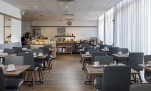 Un café moderne avec un long comptoir, un espace salon et une cuisine située à l’arrière.