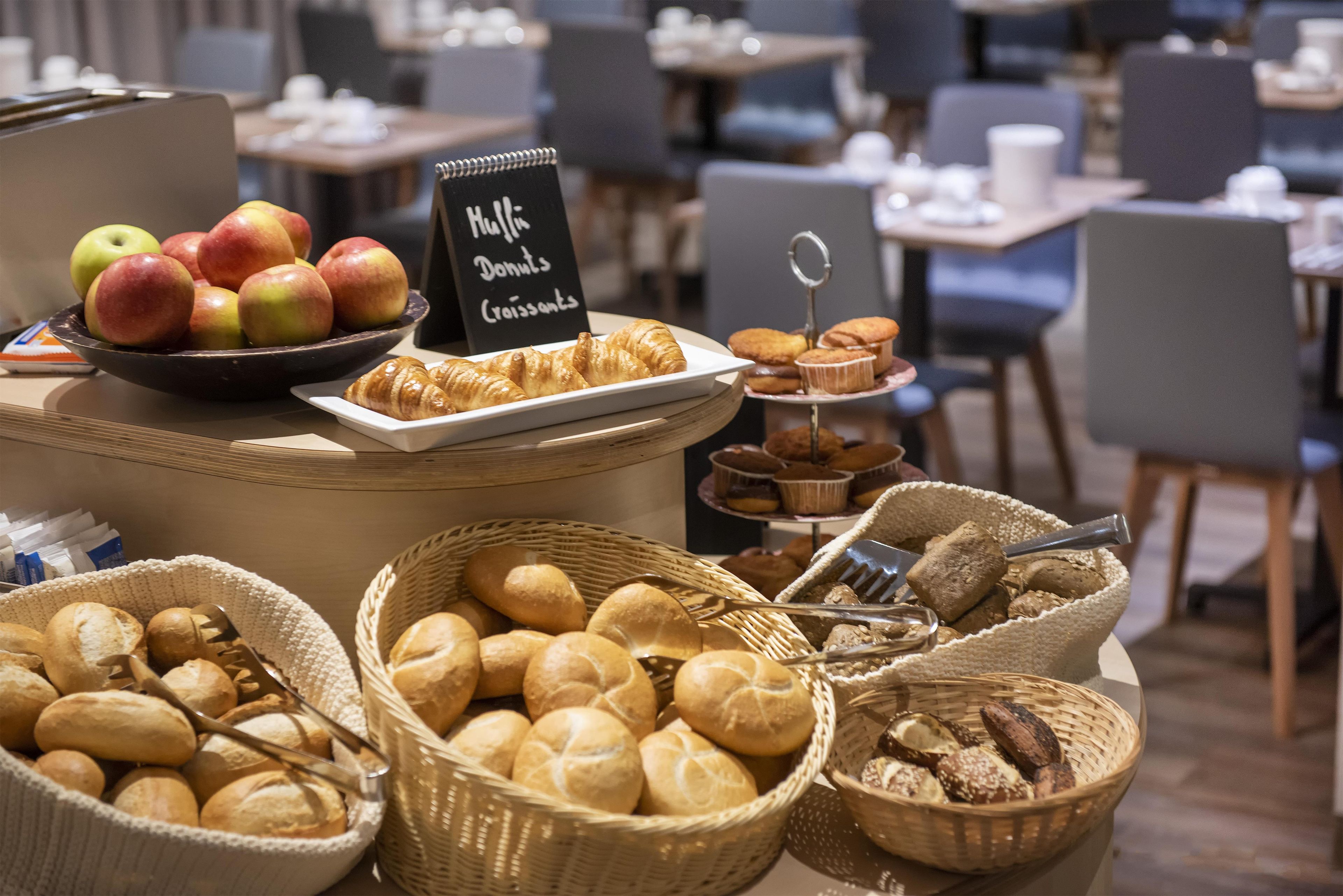 Un bufé de desayuno con panes, bollería y frutas variadas.