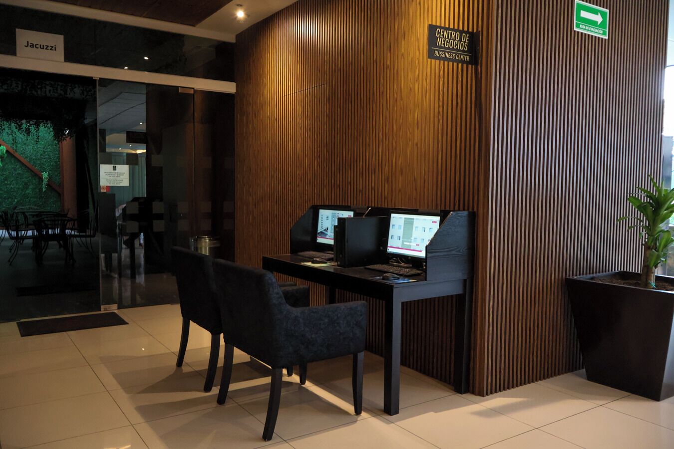 A business center with two computer workstations, a reception desk, and a sign indicating the location.