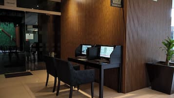A business center with two computer workstations, a reception desk, and a sign indicating the location.