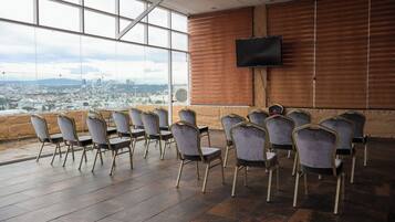Un salón de conferencias con vista a la ciudad, un televisor de pantalla plana y sillas modernas.