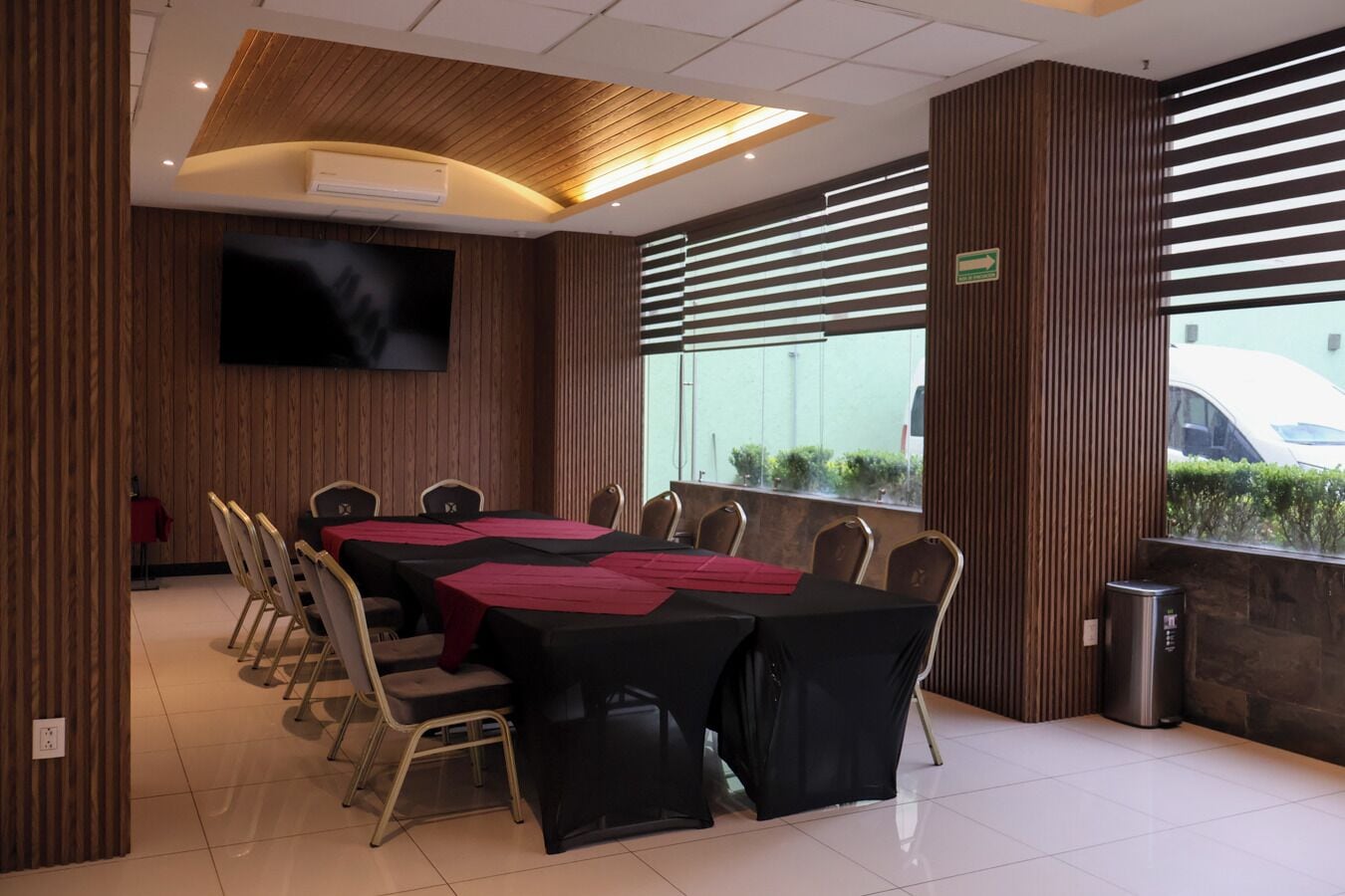 Une salle de conférence avec une longue table, des chaises, un écran de télévision et une vue par la fenêtre.