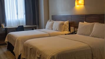 Une chambre d’hôtel avec deux lits, un bureau et une fenêtre avec des rideaux.