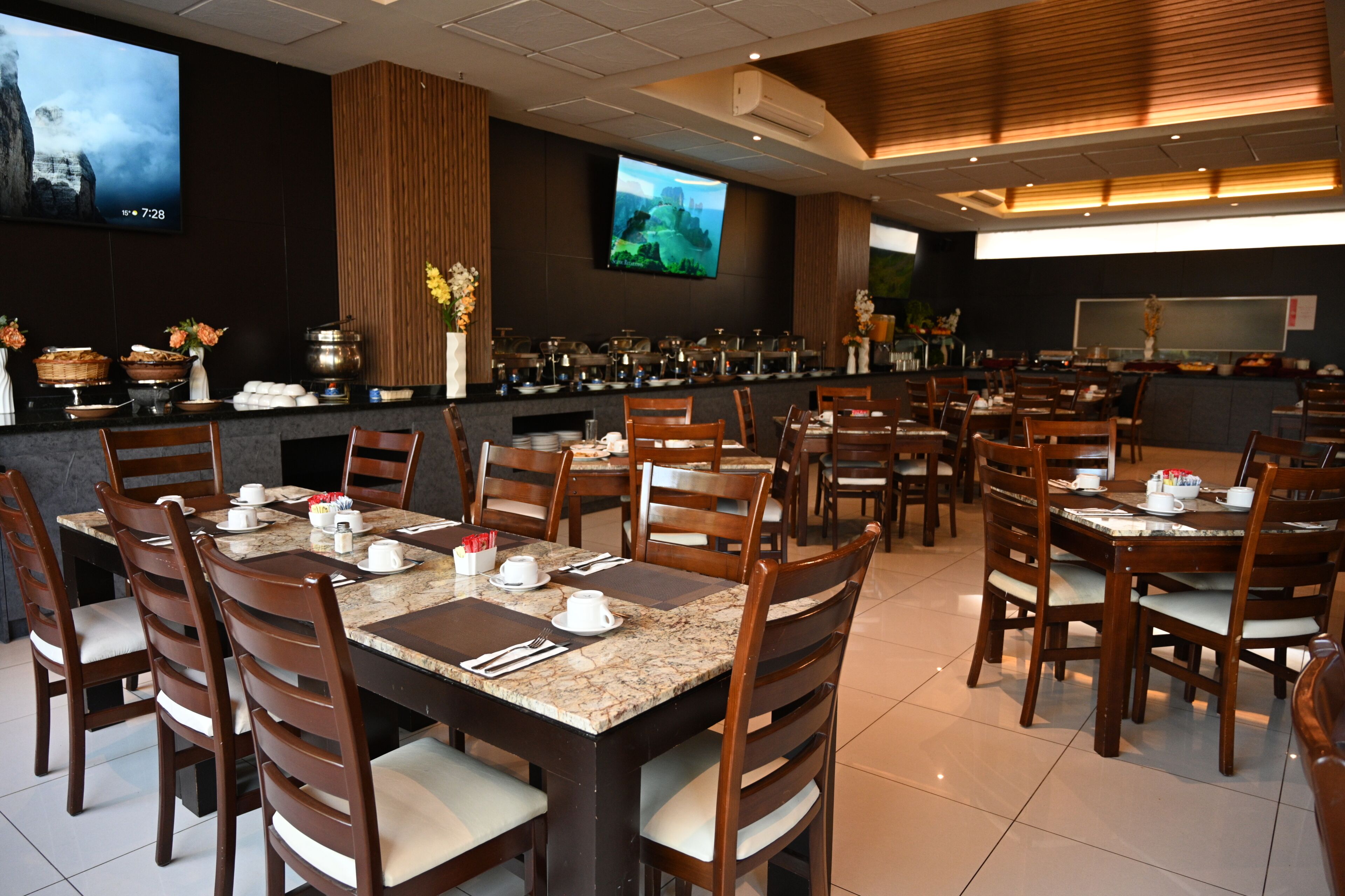 A restaurant with multiple tables and chairs, a bar area, and a television screen.