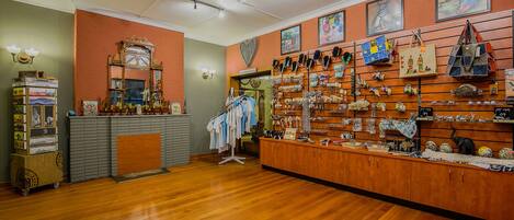 Una tienda boutique con piso de madera, un espejo y varias bolsas y accesorios exhibidos en estantes y paredes.